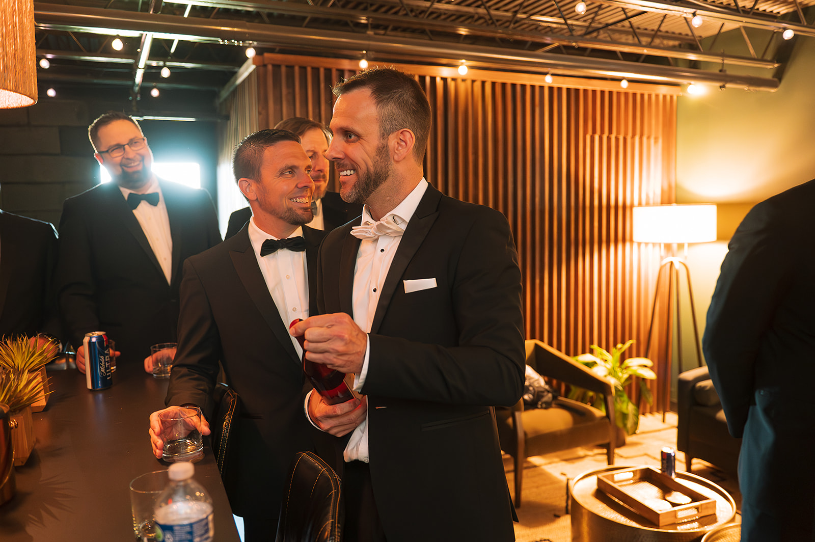 A groom opening a bottle in the groomsmen suite at Saint Elle wedding venue