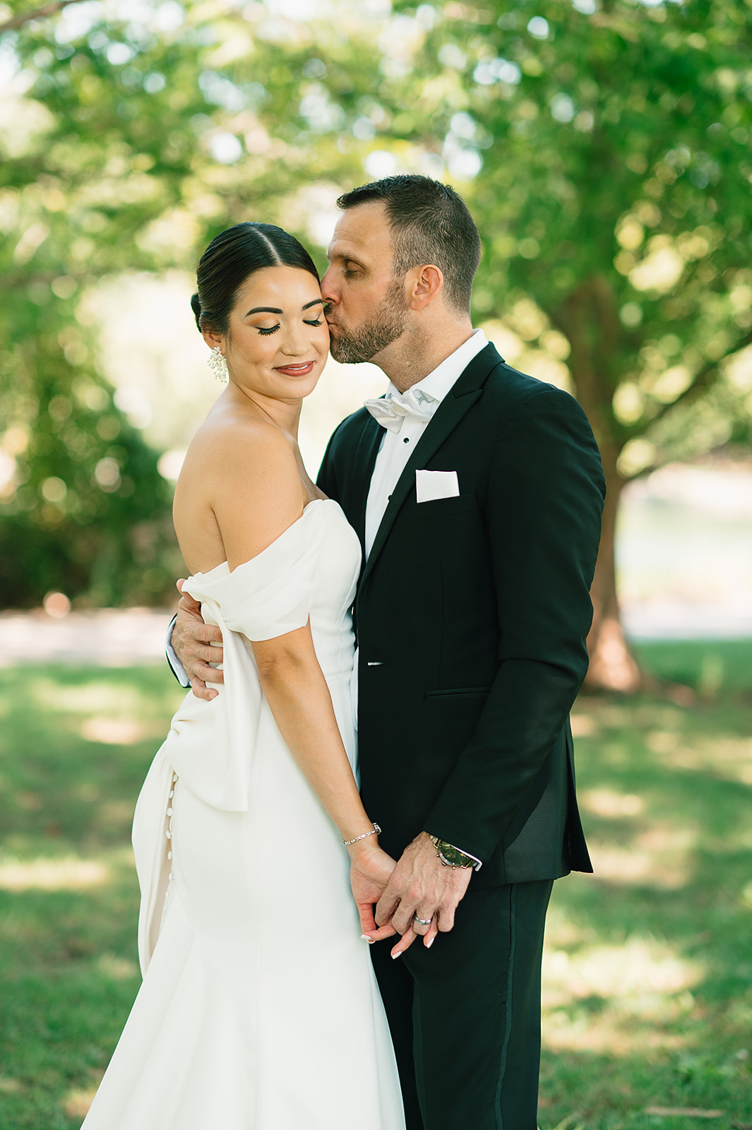 Newlyweds dance and kiss while standing out under some trees Saint Elle Wedding