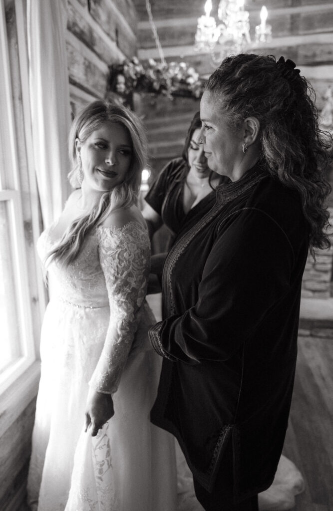 Mother of bride and sister helping bride in to dress