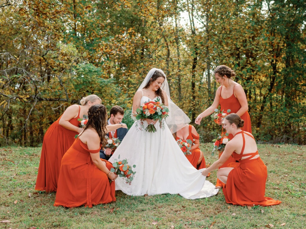 Bridesmaids assisting bride with wedding dress. 