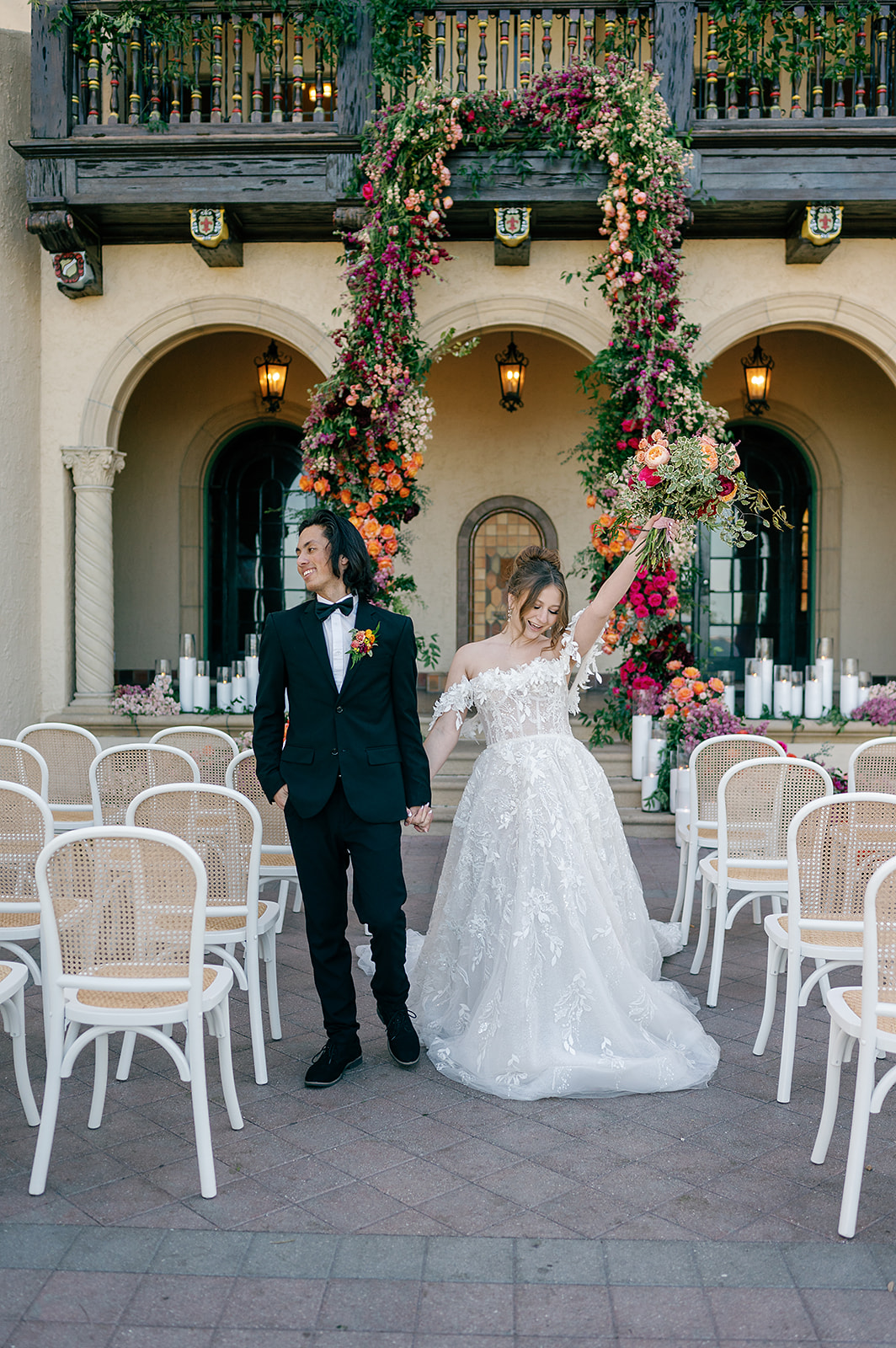 A bride and groom celebrate while walking up the aisle of an ornate wedding ceremony