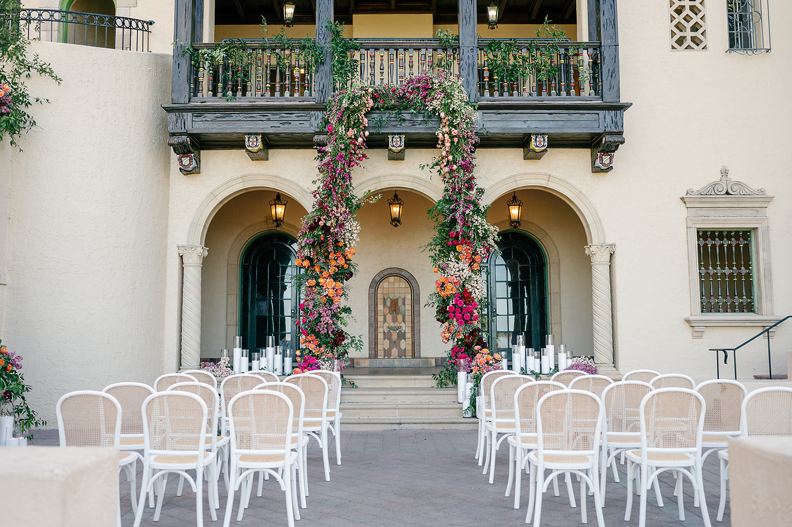 Details of a wedding ceremony set up under a balcony of a spanish style estate