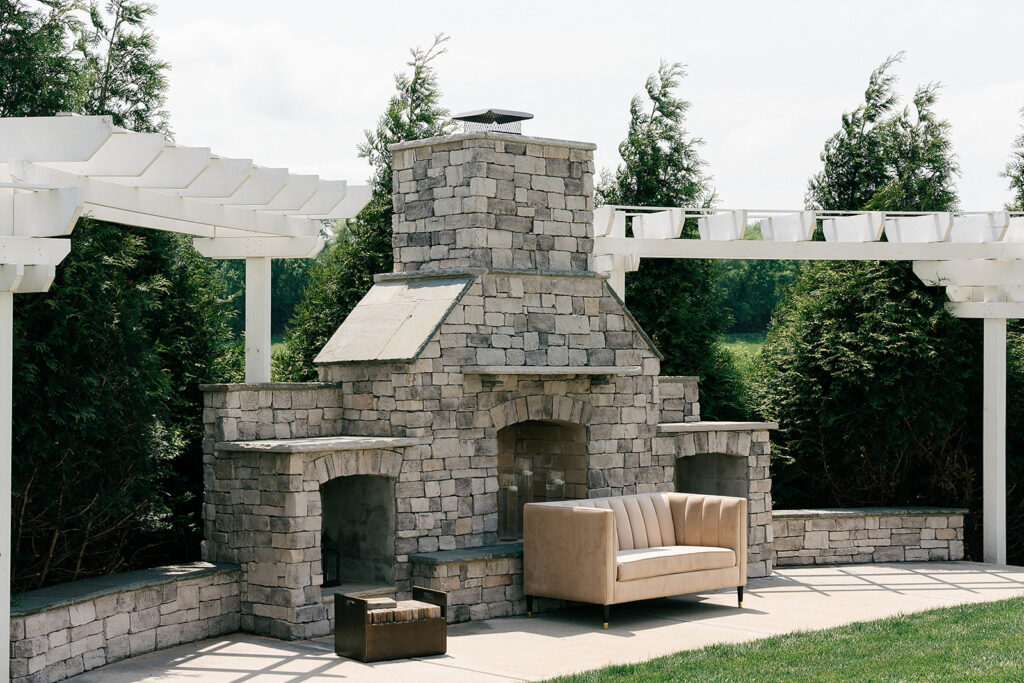 Details of a large stone fireplace on a patio lined with pergolas