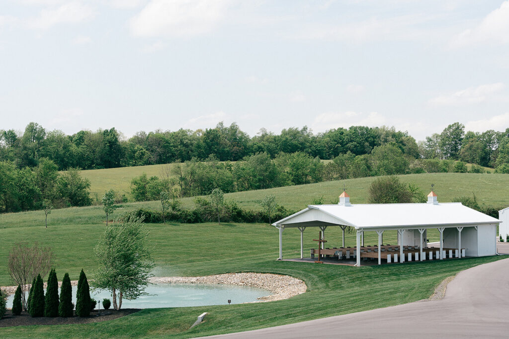 A view from the hill down to the The White Dove Barn wedding ceremony pavilion by the pond