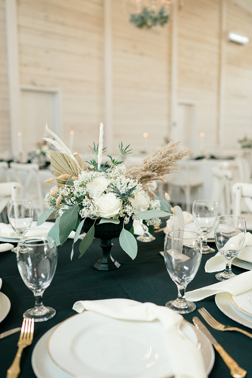 Details of a white rose centerpiece on a table with gold silverware