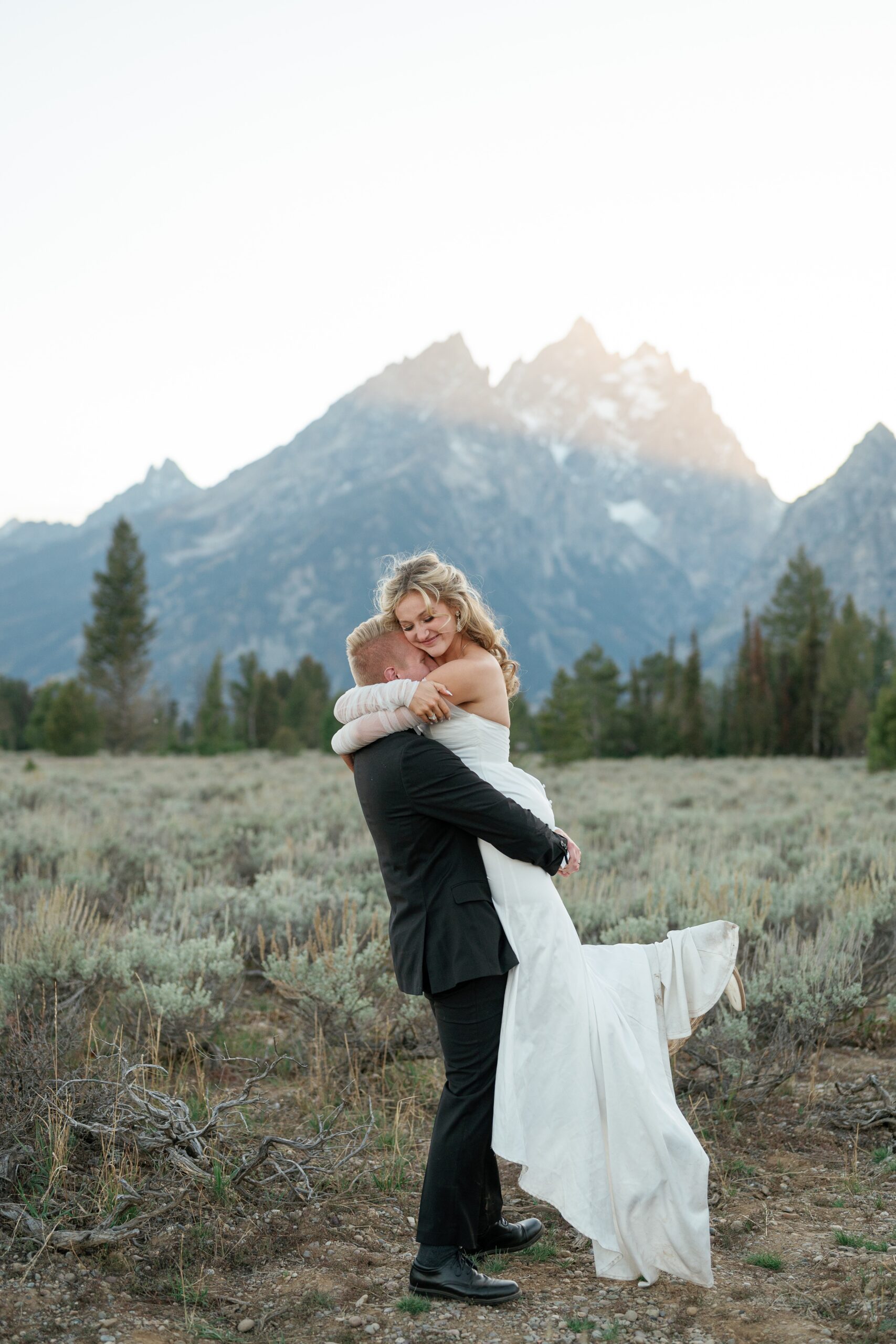 Newlyweds embrace in a mountain trail at sunset at one of the Jackson Hole Wedding venues